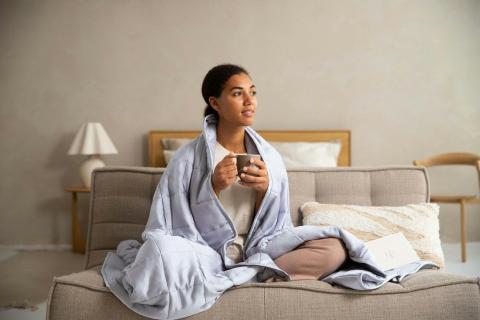 Frau sitzt mit einer Tasse auf dem Sofa