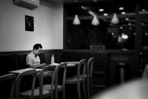 Mann sitzt allein in einem Café und schaut auf sein Smartphone