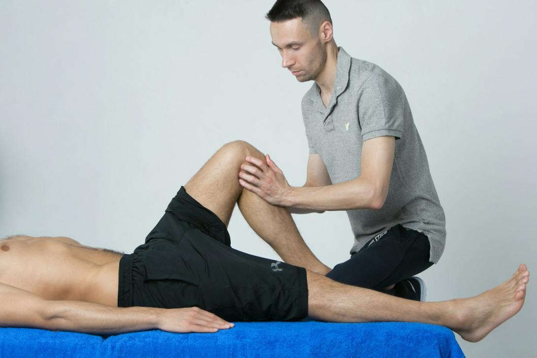Physiotherapeut untersucht das Bein eines Mannes