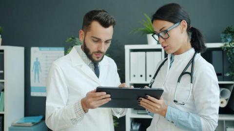 Zwei Ärztinnen und Ärzte betrachten gemeinsam ein Tablet