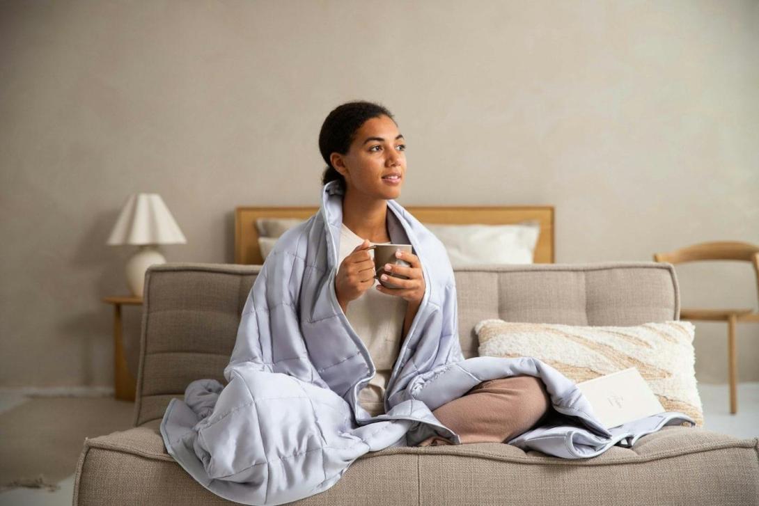 Frau sitzt mit einer Tasse auf dem Sofa