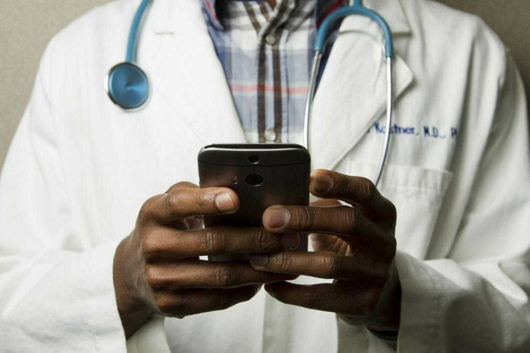 Pflegekraft mit Stethoskop schaut auf ihr Smartphone